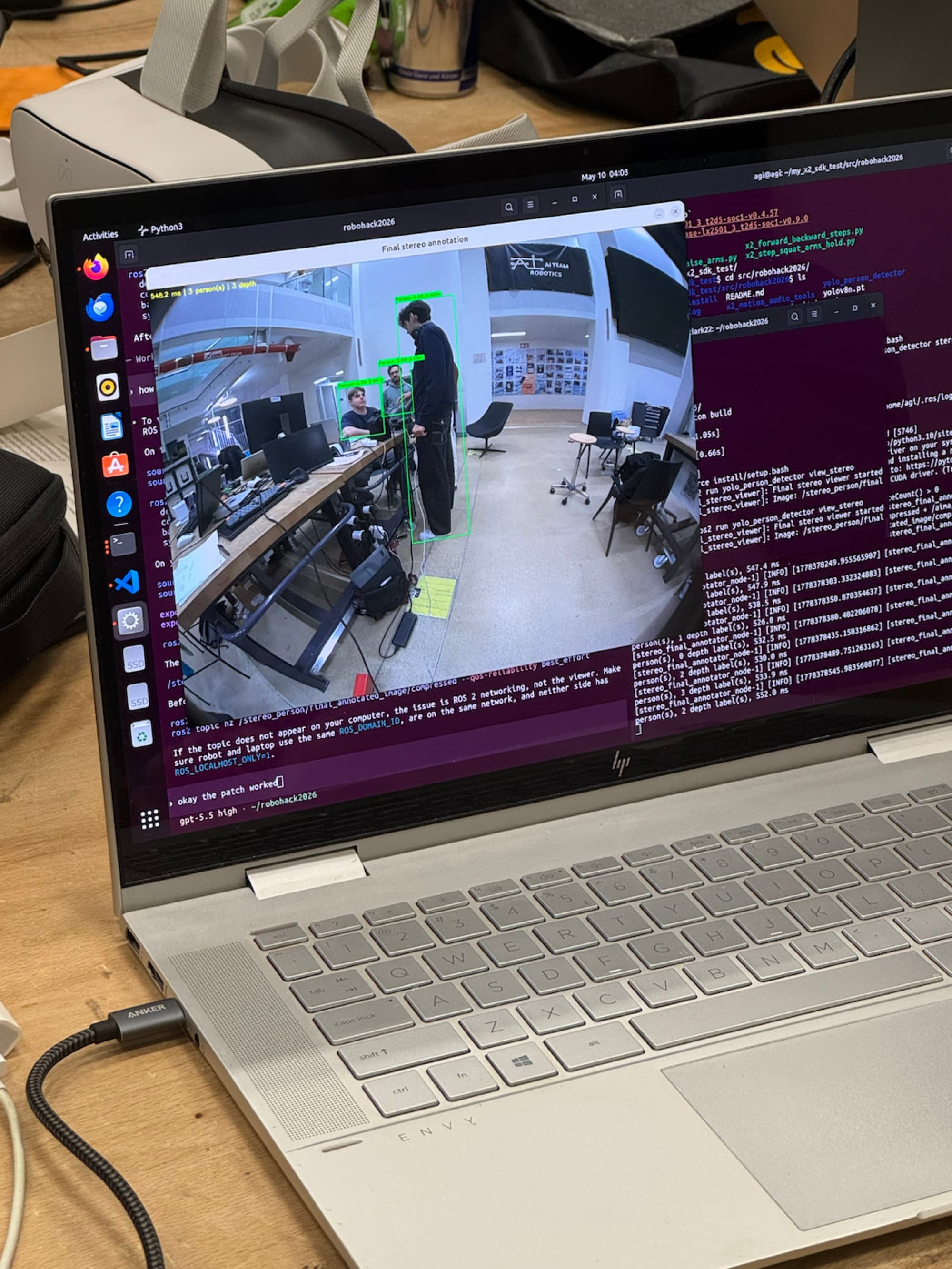 Laptop showing the live person-detection view with bounding boxes and depth labels